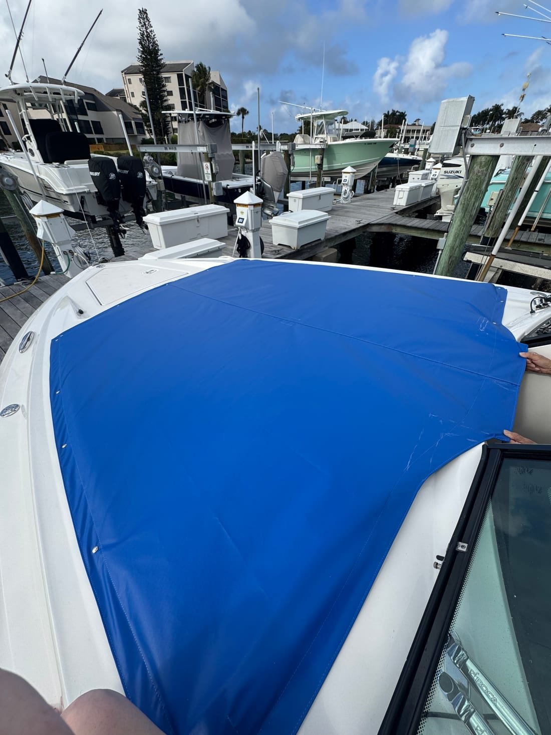 A royal blue canvas bow cover being drawn into place over a boat's foredeck
