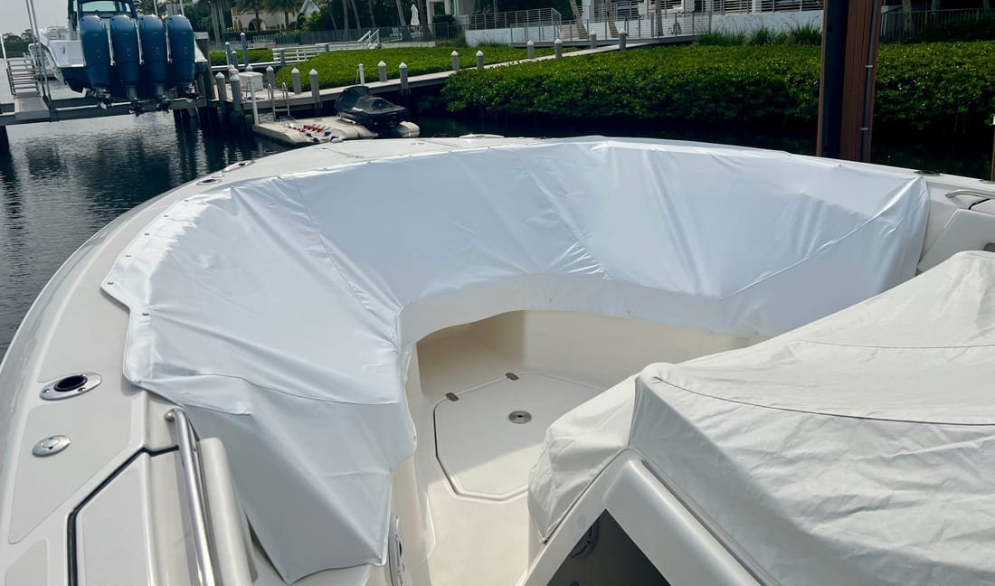 White canvas bow cover fitted over the bow seating of a center console at a seawall
