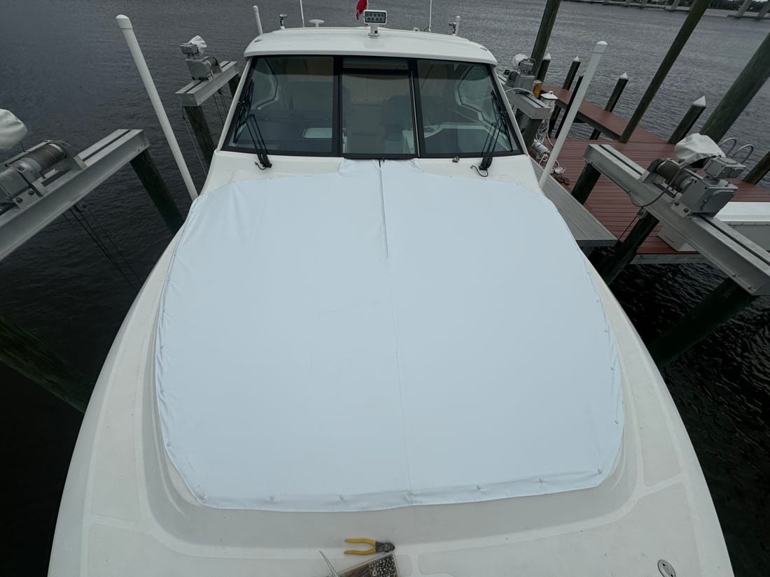 White canvas bow cover fastened over the foredeck of a sportfish boat on a lift