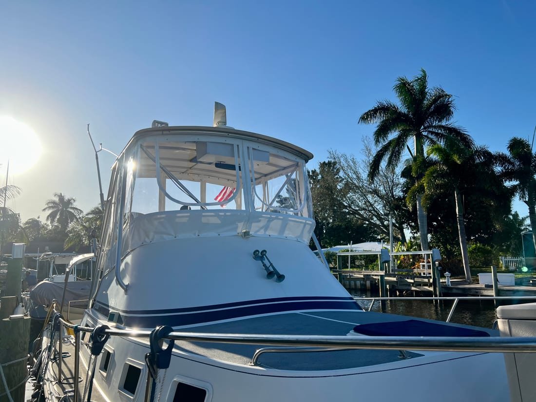 Clear vinyl bridge enclosure on a convertible sportfish at its dock, backlit by early sun