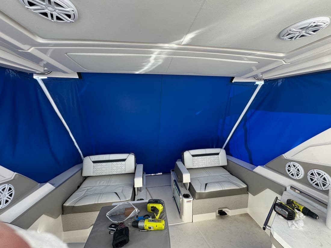 Interior of a boat's cockpit closed in with royal blue canvas panels