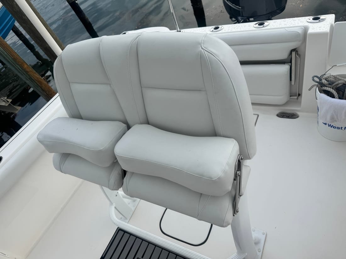 A white upholstered double helm seat with flip-up bolsters and armrests
