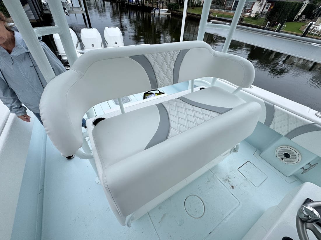 A white and grey upholstered leaning post bench on the deck of a bay boat