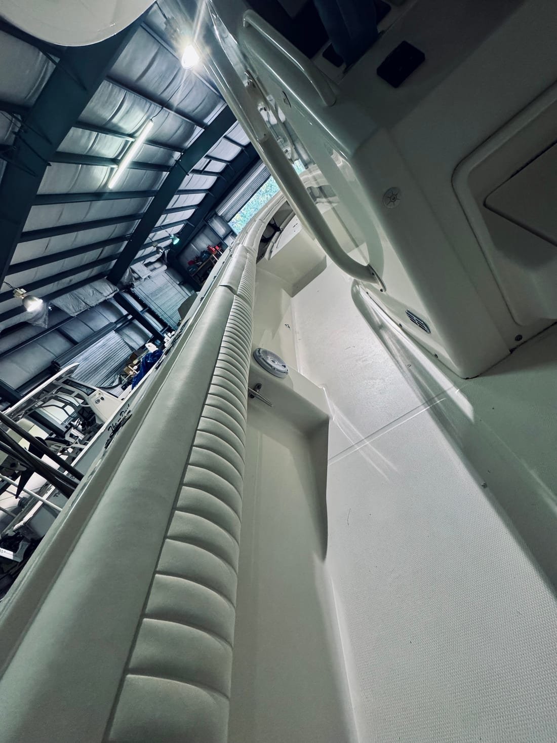 Close view along a white channel-pleated coaming bolster running the length of a boat's gunwale